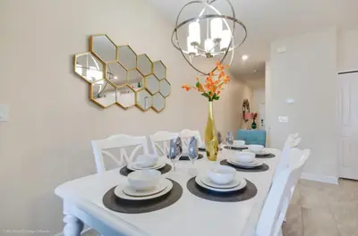 a dining room with a white table with chairs and a chandelier at Romeo Circle #239854 Townhouse in Kissimmee