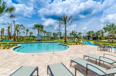 a pool at the resort with benches and palm trees at Romeo Circle #239854 Townhouse in Kissimmee