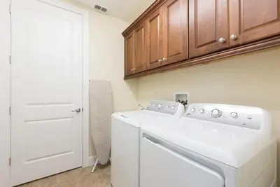 a white washer and dryer in a kitchen with wooden cabinets at Disney Dreams Luxury Home with Private Water Park in Orlando