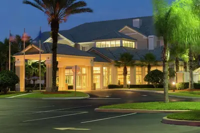 a large house with palm trees in front of it at Hilton Garden Inn Orlando East - UCF Area in Orlando
