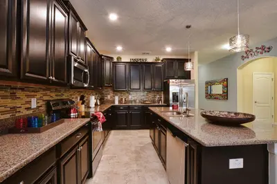 a kitchen with black cabinets and a counter top at DISNEY area Luxurious House-Private Pool in Kissimmee