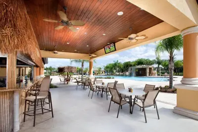 an outdoor patio with tables and chairs and a pool at DISNEY area Luxurious House-Private Pool in Kissimmee