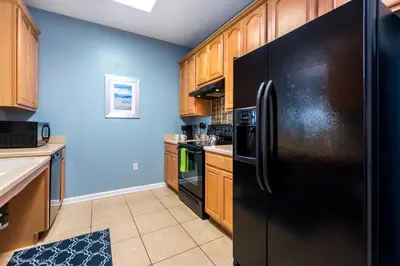 a kitchen with a black refrigerator and wooden cabinets at Stunning Top-Floor Condo, next to Clubhouse in Orlando