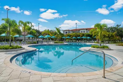 a pool at a resort with palm trees and umbrellas at Stunning Top-Floor Condo, next to Clubhouse in Orlando