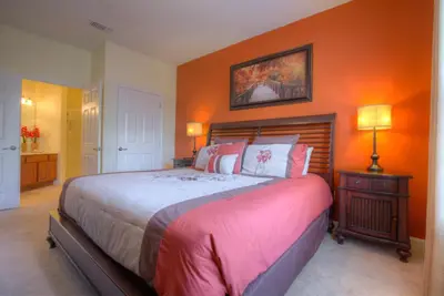 a bedroom with a large bed with an orange wall at Lofty Lodge in Orlando