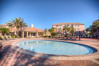 a swimming pool with chairs and a house in the background at Modern Vista Cay Condo, near Universal Studios in Orlando