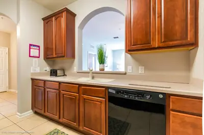 a kitchen with wooden cabinets and a black dishwasher at Spacious Condo Near Convention Ctr & I-Drive, Pool in Orlando
