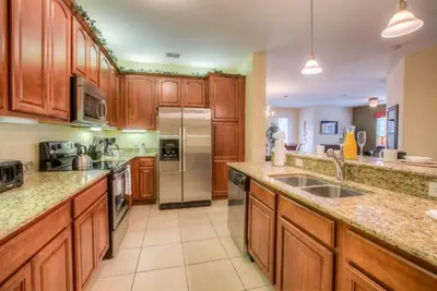 a kitchen with wooden cabinets and stainless steel appliances at Stylish Condo at Vista Cay Resort Minutes to WDW in Orlando