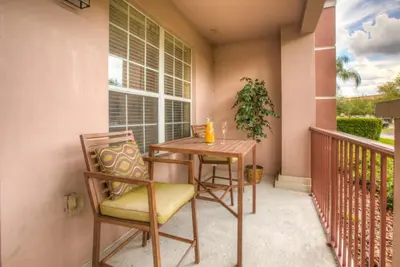 a table and chairs on a balcony with a window at Stylish Condo at Vista Cay Resort Minutes to WDW in Orlando