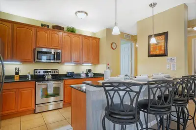 a kitchen with wooden cabinets and a table with bar stools at Beautiful Condo at Vista Cay Resort Near WDW in Orlando
