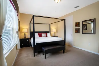 a bedroom with a canopy bed and a stool in it at Beautiful Condo at Vista Cay Resort Near WDW in Orlando