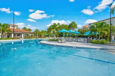 a swimming pool at a resort with blue umbrellas at Palm Villa in Orlando
