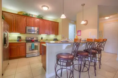 a kitchen with wooden cabinets and a island with bar stools at Palm Villa in Orlando