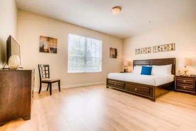 a bedroom with a bed and a desk and a tv at Newly Renovated LAKEVIEW Vista Cay Condo in Orlando