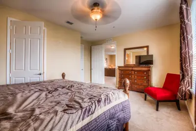 a bedroom with a bed and a chair and a mirror at Luxurious Condo wPrivate Balcony AMAZING View in Orlando