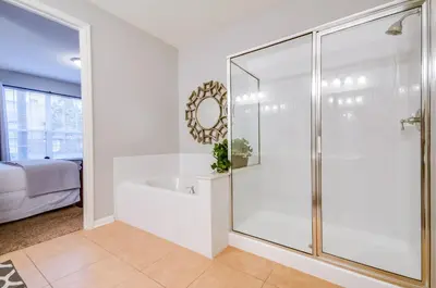 a white bathroom with a shower and a tub at Spacious Condo in Vista Cay Resort LUXURY AWAITS in Orlando