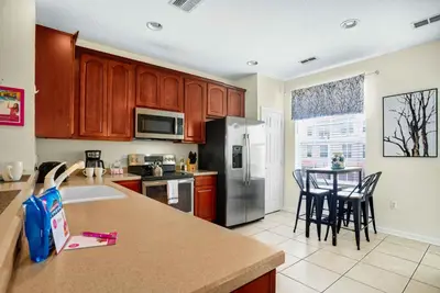 a kitchen with a refrigerator and a table with chairs at Spacious Townhome wPatio Garage Sleeps10 in Orlando