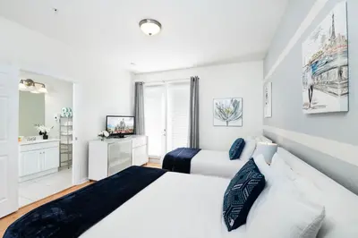 a white bedroom with two beds and a bathroom at Beautiful Newly Updated Townhome Sleeps 10 in Orlando