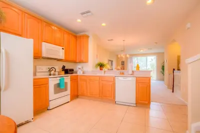 a kitchen with wooden cabinets and white appliances at Gorgeous Townhome w FREE Resort Access in Orlando