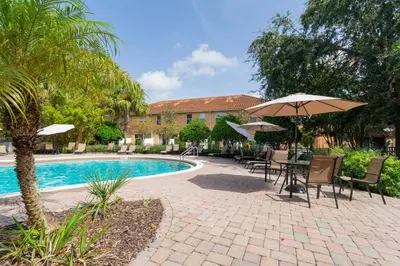 a patio with tables and umbrellas next to a pool at Four Bedrooms TownHome 5161 in Kissimmee