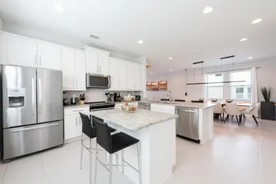 a kitchen with white cabinets and stainless steel appliances at Exquisite Home With Themed Rooms, Theater Near Disney With Waterpark & Resort Access At Encore Resort - 7736Ff in Orlando