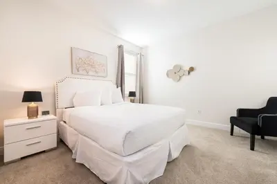 a white bedroom with a white bed and a chair at Grand Home Near Disney With Private Pool, Media And Themed Rooms With Waterpark & Resort Access At Encore Resorts Reunion - 360Bu in Kissimmee