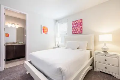 a white bedroom with a white bed and a bathroom at Luxurious Home Near Disney With Game Room And Waterpark & Resort Access At Encore Resorts Reunion - 371Fl in Kissimmee