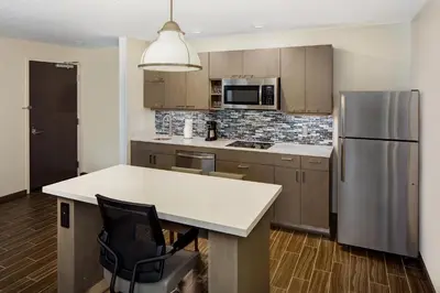 a kitchen with a refrigerator and a table with a chair at Hyatt House across from Universal Orlando Resort in Orlando
