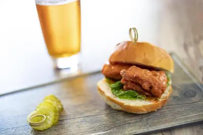 a chicken sandwich on a bun next to a pickle at Hyatt House across from Universal Orlando Resort in Orlando