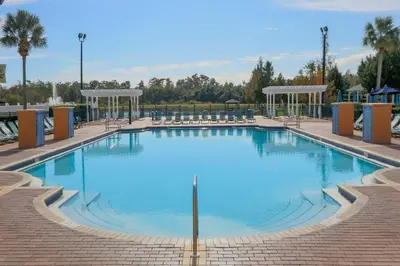 a large swimming pool with chairs around it at SPECTACULAR Home And Resort! Near Dis, Splash Park, Lake With Boats, Pool, This Home And Resort Has It ALL! Low Rates Too! in Kissimmee