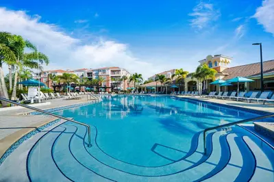 a swimming pool at a resort with palm trees and buildings at Orlando Resort Rentals at Universal Boulevard in Orlando