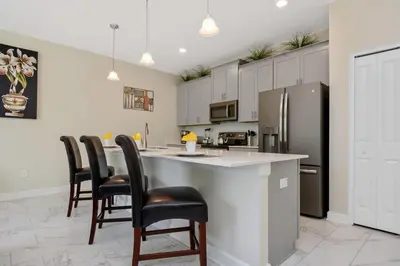 a kitchen with a bar with chairs and a refrigerator at Four Bedrooms close to Disney w Pool 4898 in Kissimmee