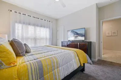 a bedroom with a bed with a yellow blanket and a television at Four Bedrooms close to Disney w Pool 4898 in Kissimmee