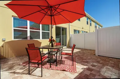 a table and chairs with a red umbrella on a patio at Family Friendly 4 Bedroom Close to Disney 5148 in Kissimmee