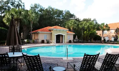 a swimming pool with chairs and an umbrella at Four Bedroom w/ GameRoom 5152A in Kissimmee