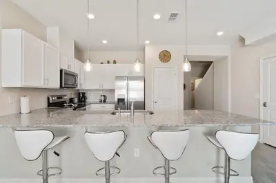 a kitchen with white cabinets and a counter with stools at Family Friendly Four Bedrooms 5147A in Kissimmee