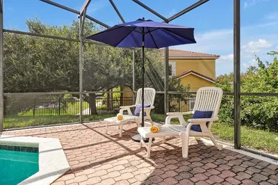 two chairs and an umbrella next to a swimming pool at Encantada Resort Vacation Townhomes by IDILIQ in Kissimmee