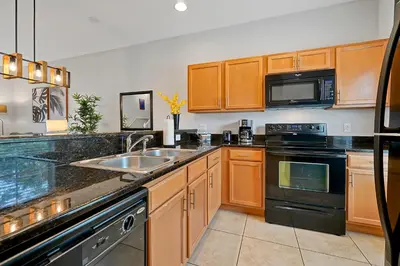 a kitchen with wooden cabinets and a sink and appliances at Encantada Resort Vacation Townhomes by IDILIQ in Kissimmee