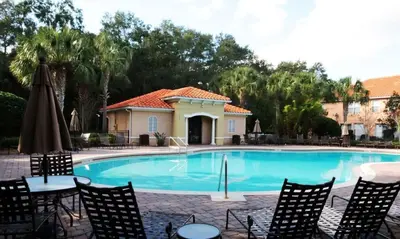 a swimming pool with chairs and a house at Four Bedroom with GameRoom 5150A in Kissimmee