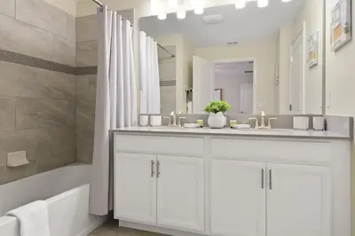 a white bathroom with a sink and a tub at Four Bedrooms with Screen PoolStoreyLake 4910 in Kissimmee