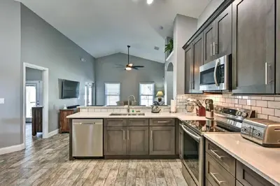 a large kitchen with stainless steel appliances and wooden cabinets at Mickeys Landing - Luxurious 4BR with 2 Master Suites, Privacy Fenced Pool & Hot Tub BBQ Game RM 2 miles to Disney! in Orlando