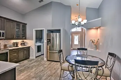 a kitchen with a table and chairs and a refrigerator at Mickeys Landing - Luxurious 4BR with 2 Master Suites, Privacy Fenced Pool & Hot Tub BBQ Game RM 2 miles to Disney! in Orlando