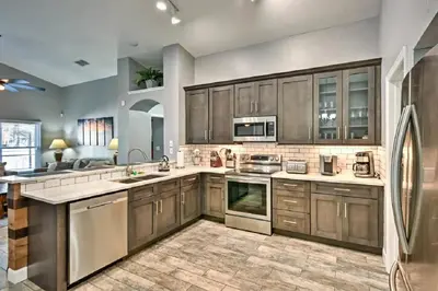 a large kitchen with wooden cabinets and stainless steel appliances at Mickeys Landing - Luxurious 4BR with 2 Master Suites, Privacy Fenced Pool & Hot Tub BBQ Game RM 2 miles to Disney! in Orlando