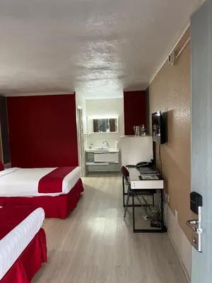 a hotel room with two beds and a sink at Travelodge by Wyndham Orlando at Heart of International Drive in Orlando
