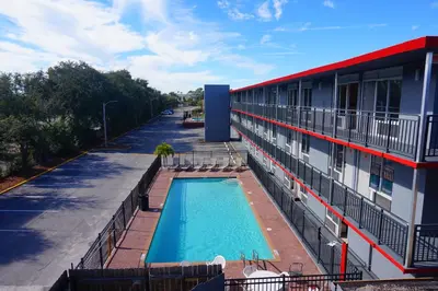 a building with a swimming pool next to a building at Travelodge by Wyndham Orlando at Heart of International Drive in Orlando