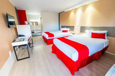 a hotel room with two beds and a television at Travelodge by Wyndham Orlando at Heart of International Drive in Orlando