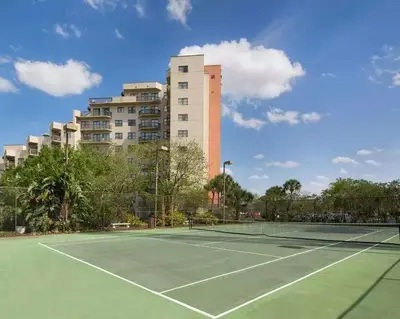 a tennis court with a building in the background at Enclave Apartments at International Drive in Orlando