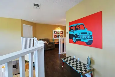 a living room with a painting of a car on the wall at Aquamarine Hideaway in Kissimmee