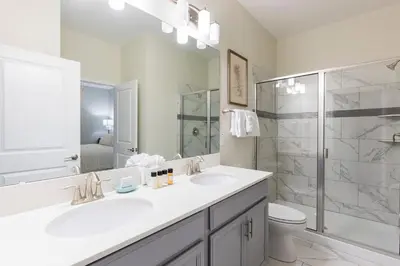 a white bathroom with two sinks and a shower at Modern Luxury Villa with Everything in Kissimmee