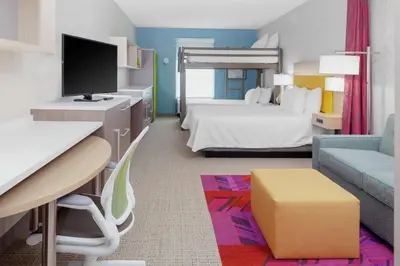 a hotel room with a bedroom with a bed and a tv at Home2 Suites By Hilton Orlando South Park - Near Epic Universe in Orlando